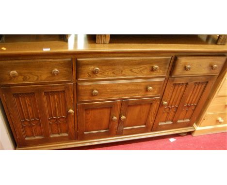 A contemporary Ercol mid-elm sideboard, fitted with four drawers and four cupboard doors, on bun supports, w.155cm