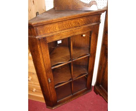 A contemporary joined oak single door glazed hanging corner cupboard, having twin bracket supports, h.103cm
