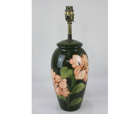 A Moorcroft pottery table lamp in the hibiscus pattern in peach on green ground, 38cm high