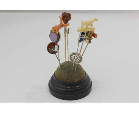 Eight various stick and lapel pins on a stand