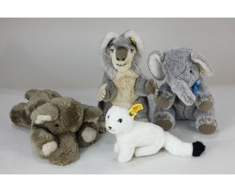 Four Steiff soft toys, a koala, an elephant with blue bow, an ermine (winter stoat), and an elephant lying down, all with yel