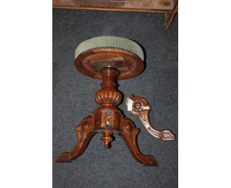 A Victorian mahogany piano stool with upholstered circular studded seat, adjustable baluster stem with floral carved outswept