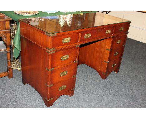 A modern mahogany brass bound campaign style pedestal desk with nine drawers, on bracket feet, 122cm