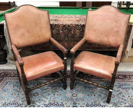A pair of studded leather covered oak framed open arm throne type chairs in the 17th Century style raised on bobbin turned su