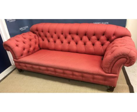 A circa 1900 Chesterfield sofa with button back and scroll arms, raised on waisted legs to brass caps and castors, 200 cm wid