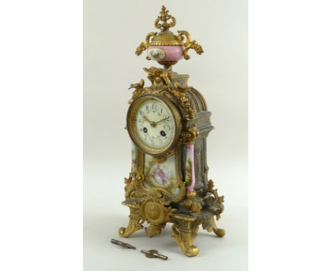 A late 19th / early 20th century clock, likely French, painted pink ceramic pillars to either side of gilded brass body, eigh