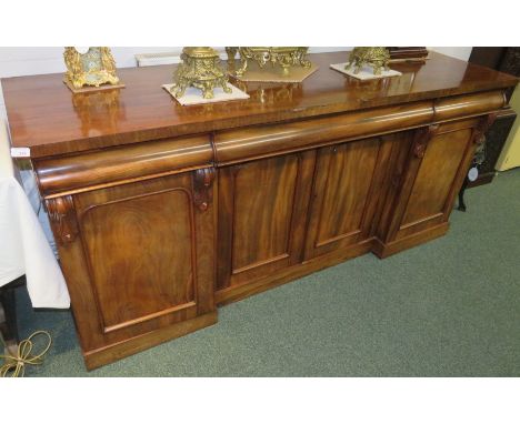 A large early Victorian mahogany sideboard with three cushion drawers over a central double cupboard enclosing a single shelf