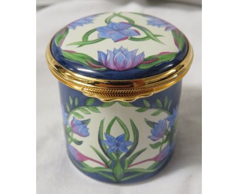 Moorcroft enamel cylindrical pill box with hinged lid, blue ground and cream with panels of blue lilies, height 4.5cm, diamet