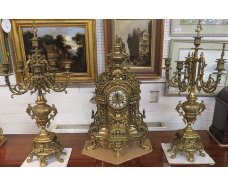 A German Franz Hermle striking mantle clock in a heavy cast brass frame with two heavily decorated five branch candelabrum an