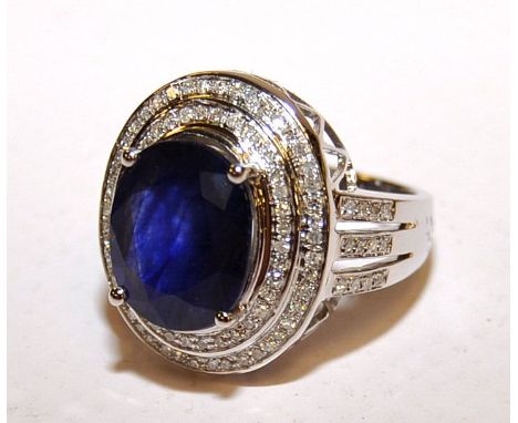 A 14K WHITE GOLD AND DIAMOND RING SET WITH AN OVAL CUT BLUE SAPPHIRE 