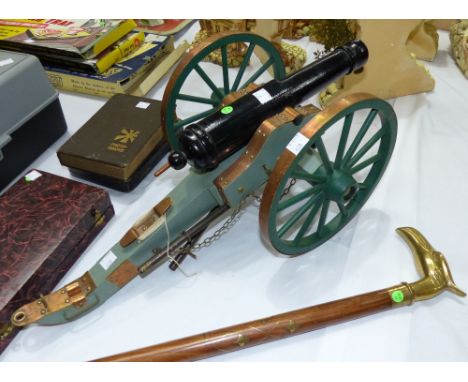 A painted wooden copper bound model cannon; a modern brass inlaid walking stick