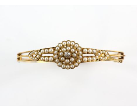 Victorian bangle, centrally set with an old cut diamond, estimated diamond weight 0.16 carats, set within borders of white pe