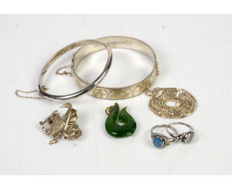 A jewellery box containing costume jewellery, including a floral bangle, another similar oval bangle, a dragon brooch, a moon