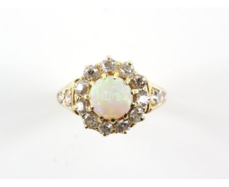 Opal and diamond cluster ring, centrally set with a round cabochon cut opal 7.4 x 7.4mm, surrounded by a border of old cut di