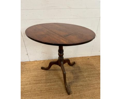 A circular oak tilt top table on turned central support and splayed tripod legs (H66cm Dia71cm 