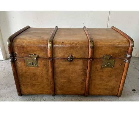A vintage wooden banded steamer trunk with brass fittings and leather strap handles to ends opening to a relined black and sc