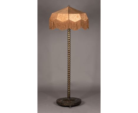 A mid-20th Century Arts and Crafts style brass plated metal standard lamp, the spiral twisted stem above a circular base, dec