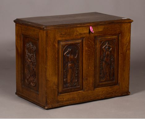 An early 20th Century Arts and Crafts style oak trunk, the hinged lid above a panelled front carved with maidens, raised on c