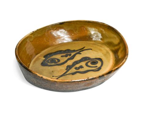 § Charles Tustin (1922-1966) at WInchcombe Pottery, a slipware dish, of high-sided elliptical form decorated with fish, impre