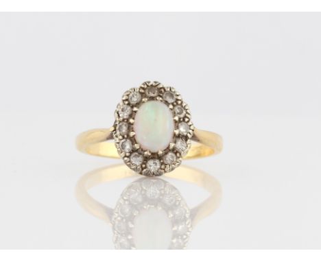 An opal and diamond cluster ring, set with an oval opal cabochon, measuring approx. 7x5mm, surrounded by a border of twelve e