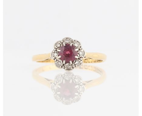 An 18ct yellow gold ruby and diamond cluster ring, set with a central round cut ruby (possibly synthetic), surrounded by a bo