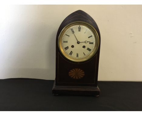 A mahogany mantle clock with gothical form, bun feet and Roman numerals to face.