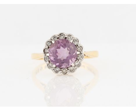 An amethyst and diamond cluster ring, set with a central round cut amethyst, surrounded by a border of fourteen eight-cut dia