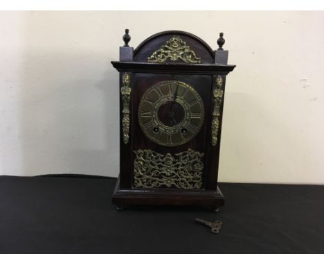 A mahogany mantle clock with brass face and decoration and Roman numerals to face