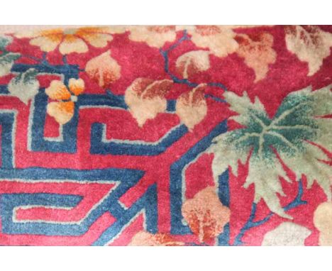 LARGE CHINESE CARPET
with floral and scrolling design in pink, yellow and blue on a bright red ground