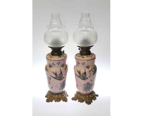 Pair of enamel and ormolu oil lamps decorated with floral and bird scenes with etched glass shades
