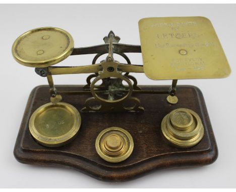 A late Victorian set of brass postal scales, on polished wood base, the plate engraved with postal rates, having weights to b
