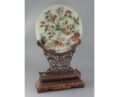 A Chinese hardstone circular plaque and hongmu stand, early 20th century, the plaque decorated with peonies and rockwork in s