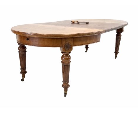 Edwardian mahogany oval wind out extending dining table, with floral carved roundels, raised on turned tapered and fluted sup