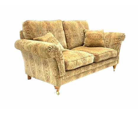 Parker Knoll - two seat sofa, upholstered in golden medallion fabric, with two small cushions and supported by two brass cast