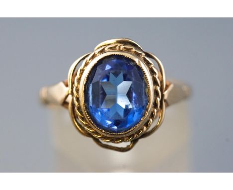 A yellow metal single stone ring, set with an oval blue glass gem, hallmarked 9ct gold, Birmingham. Size: O 3.2 grams