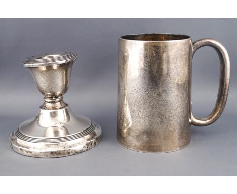 A plain silver cylindrical tapered mug, London 1920, 9cm high, 172 grams, and a loaded silver candlestick