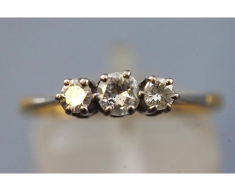 A yellow and white metal three stone diamond ring, set with three graduated round brilliant cut diamonds. Estimated total wei