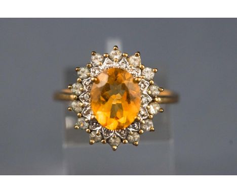 A yellow and white metal cluster ring, set with an oval faceted cut citrine, surrounded by an illusion setting having three r