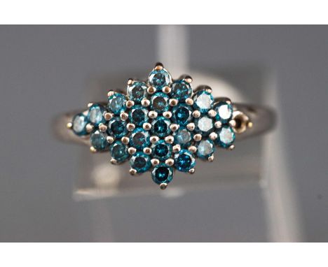 A white metal cluster ring set with round faceted cut treated blue diamonds (one is missing). Hallmarked 9ct gold, Sheffield.