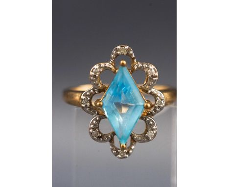 A yellow and white metal dress ring, set with a central diamond shaped blue topaz and surrounded by petals each set with a si