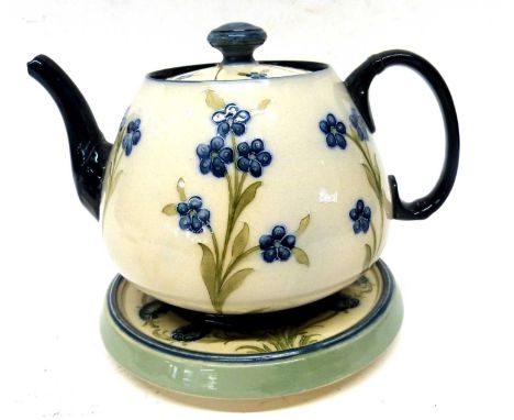A Macintyre Burslem teapot and cover with matching stand with tubelined floral decoration by William Moorcroft (3)stand 16cm 
