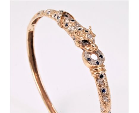 A sapphire and diamond bangle, with stylised leopard head holding a sapphire and diamond ring in its mouth, further set with 