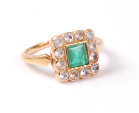 An emerald and white hardstone cluster ring, the step cut emerald in rubover mount, surrounded by small round white hardstone