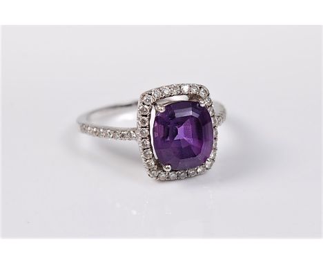 An 18ct white gold amethyst and diamond ring, the modified cushion cut amethyst, approx. 8.6 x 7.7mm, in a four claw mount wi