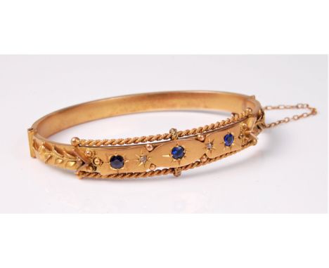 A sapphire and diamond hinged bangle, the three round sapphires (one a doublet) set with diamond highlights, between a rope t