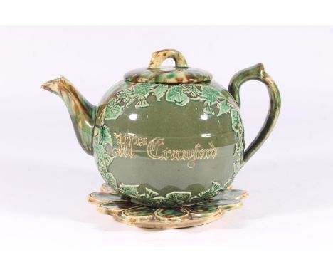 Victorian Dunmore pottery Majolica teapot, of mottled green and brown glaze around an ivy framed cartouche, on matching stand