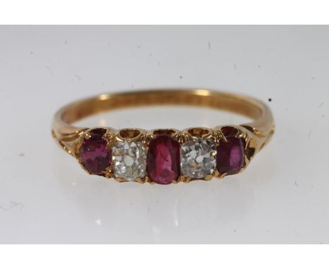 18ct gold ruby and diamond ring, the three oval cut diamonds separated by round cut diamonds, on scrolled shoulders leading t