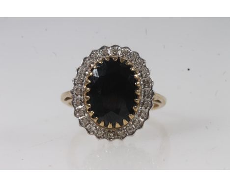 9ct gold sapphire and diamond cluster ring, the large oval cut dark sapphire within a halo of small round cut diamonds, on a 