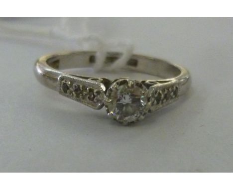 An 18ct white gold single stone claw set solitaire diamond ring, flanked by chipped shoulders         11