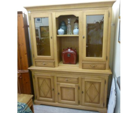 A modern light oak living room display unit, having a moulded cornice, over two open shelves, flanked by a pair of glazed doo